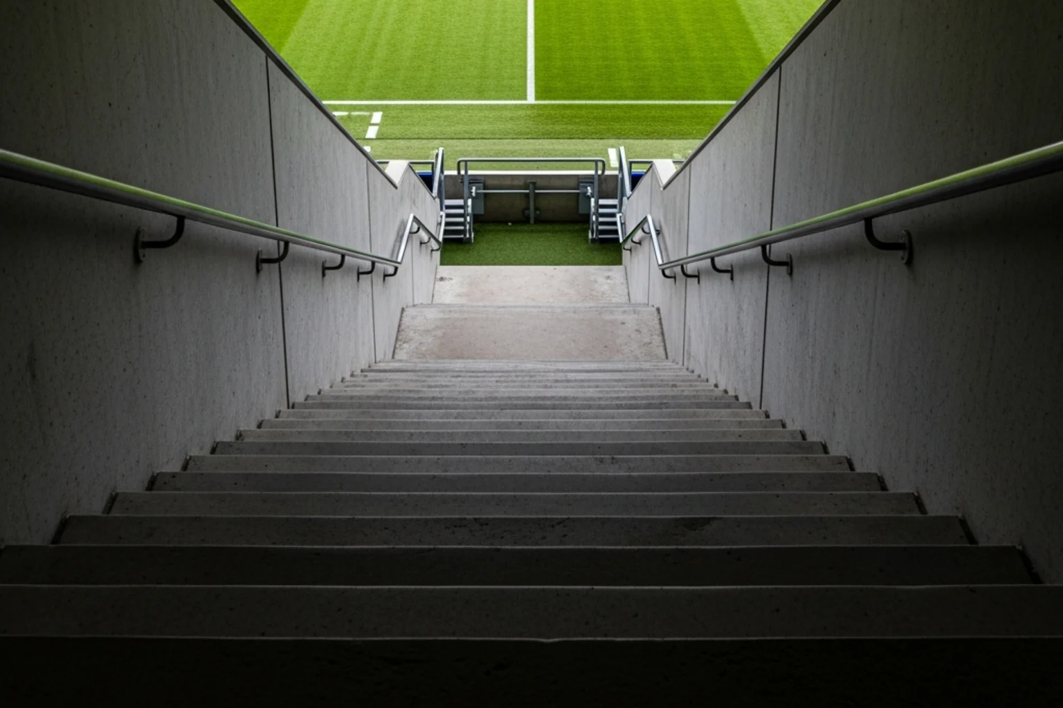 Escalera ascendente con césped verde de estadio al final simbolizando el ascenso deportivo
